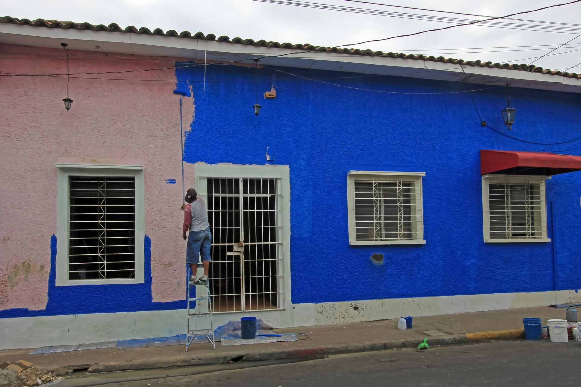 Man painting a colorful house in the streets of the colonial city of Leon, Nicaragua, Central America